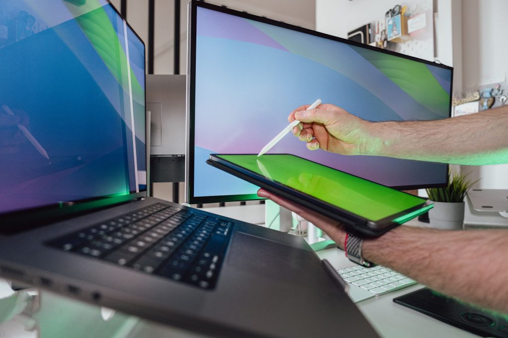 men hands holding tablet over laptop and monitor